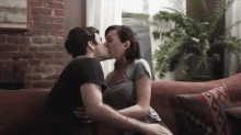 a man and woman are kissing on a couch .
