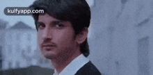 a man in a black jacket and white shirt is looking at the camera .