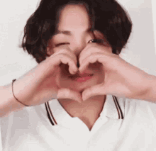a young man is making a heart with his hands .