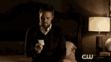 a man is sitting on a bed in a dark room holding a piece of paper .