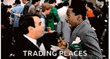two men are talking in front of a crowd of people in a trading places scene .
