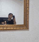 a man taking a picture of himself in a mirror with a gold frame