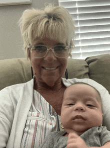 a woman wearing glasses is holding a baby in her arms