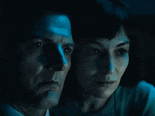 a man and a woman are looking at something in a dark room in a movie .