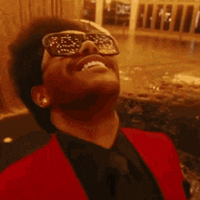 a close up of a man wearing sunglasses and laughing with his mouth open .