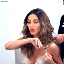 a woman wearing a very plunging top is getting her hair cut by a man with the name anahiacc behind her