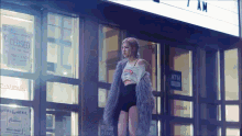 a woman in a fur coat is standing in front of a building that is closed