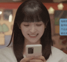 a woman is smiling while holding a cell phone