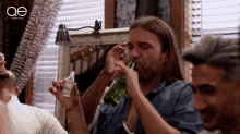 a man drinking from a green bottle with a ae logo on the bottom