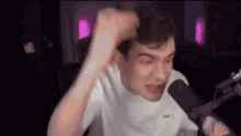 a man is screaming into a microphone while holding his head .