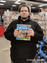 a man in a black hoodie holds up a box of super gigant
