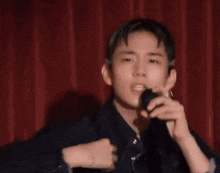 a young man is singing into a microphone while wearing earrings .