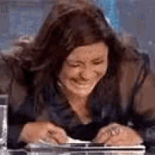 a woman is crying while sitting at a table with a tablet and a glass of water .