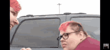 a woman with pink hair and glasses is standing next to another woman with red hair .