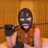 a woman wearing a black lace mask is holding a whip in her hand