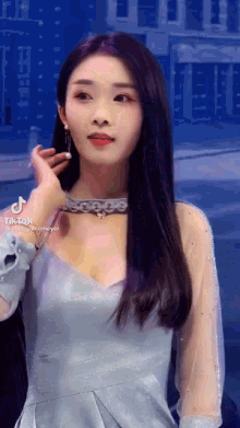 a woman in a blue dress is standing in front of a building and looking at the camera .