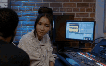 a woman in a pearl jacket sits in front of a computer screen