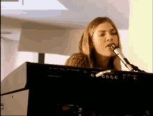 a woman is singing into a microphone while playing an electronic keyboard .