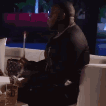 a man is smoking a cigarette while sitting on a couch in a dark room .