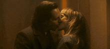 a man and a woman are kissing against a wall
