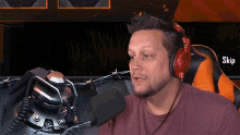 a man wearing red headphones is sitting in front of a microphone with the word skip on the bottom right