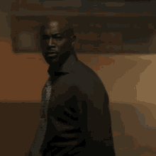 a man wearing a black shirt and tie is standing in a dark room .