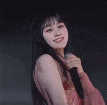 a woman in a pink dress is holding a microphone and smiling
