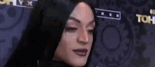 a close up of a woman 's face with black hair and purple lipstick .