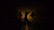 three women in gold dresses stand in front of a yellow light