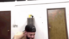 a man with a beard wearing a baseball cap is standing in a room with a door .