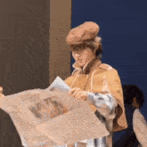 a man in a cape is reading a newspaper with a picture of a woman on it