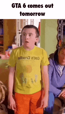 a boy wearing a yellow shirt that says ' gta 6 comes out tomorrow ' on it .