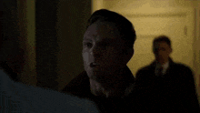 a man in a black hat is fighting another man in a white shirt in a room .