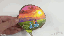 a person holding a piece of wood with a painting of two people on scooters
