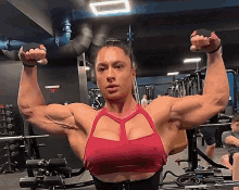 a woman in a red top is flexing her muscles