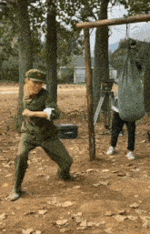a man in a military uniform is standing in a field with a bag hanging from a pole