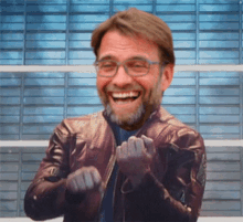 a man wearing glasses and a leather jacket laughs