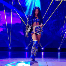 a female wrestler is standing on a stage holding a wrestling belt .
