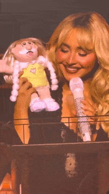 a woman holds a stuffed doll and a microphone
