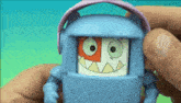 a person is holding a toy that looks like a robot with headphones on .