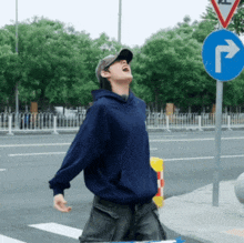 a man in a blue hoodie is standing in front of a street sign that says r.