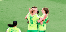 a group of female soccer players hugging each other on a field .