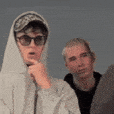 a boy wearing a hoodie and sunglasses looks surprised