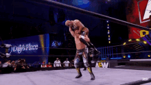 a wrestler is carrying another wrestler on his back in a wrestling ring