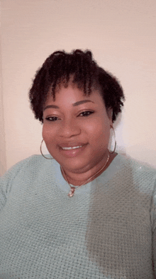 a woman wearing a light blue sweater and gold hoop earrings