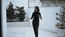 a woman in a black shirt and black pants is standing in front of a white wall made in animotica