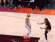two women are playing basketball on a court and one of them is wearing pink shoes