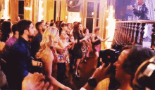 a group of people are dancing in a room while a man stands behind them
