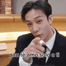 a man in a suit and tie is pointing at the camera and says pau te amo solo a ti .