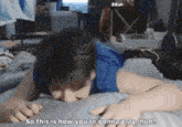 a man in a blue shirt is laying on a bed and talking to another person .